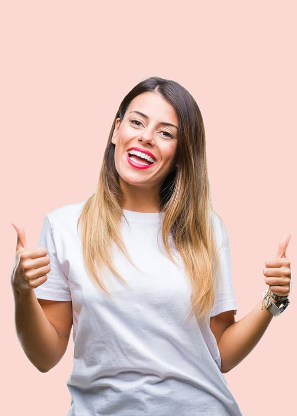 Donna sorridente con i pollici alzati su sfondo rosa cipria